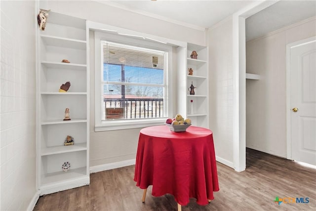 dining area with built in shelves, ornamental molding, baseboards, and wood finished floors