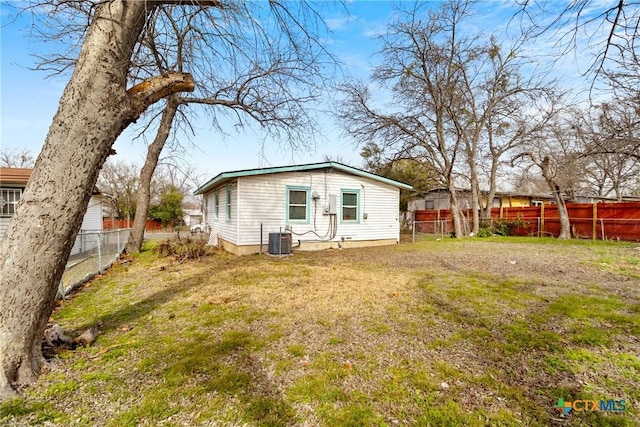 rear view of property with central AC, a lawn, and fence