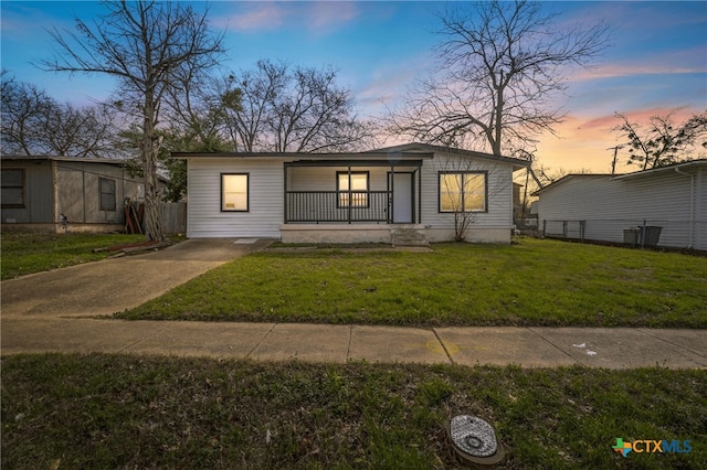 view of front of property with covered porch, a yard, and fence