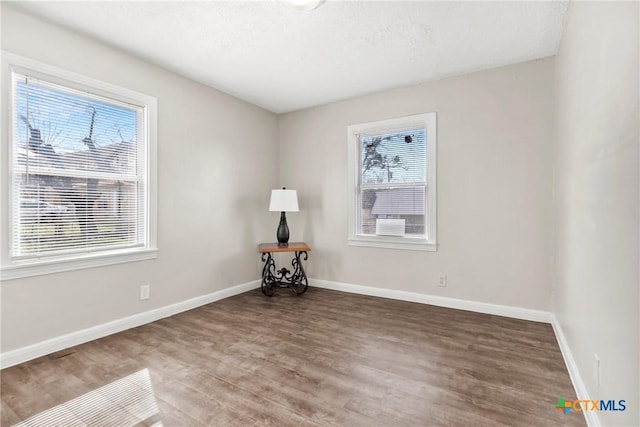 spare room featuring wood finished floors and baseboards