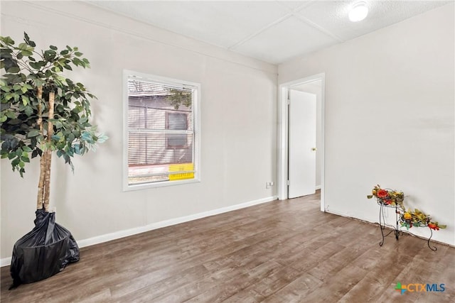 empty room with baseboards and wood finished floors