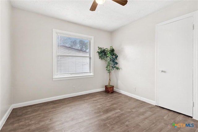 unfurnished room with wood finished floors, a ceiling fan, and baseboards