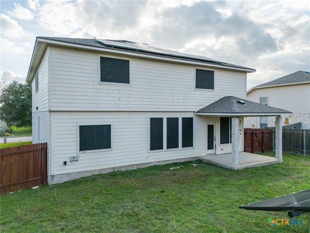 rear view of house featuring a yard, a patio, and solar panels