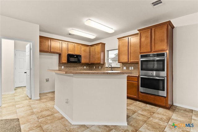 kitchen with tasteful backsplash, sink, a kitchen island, and stainless steel double oven