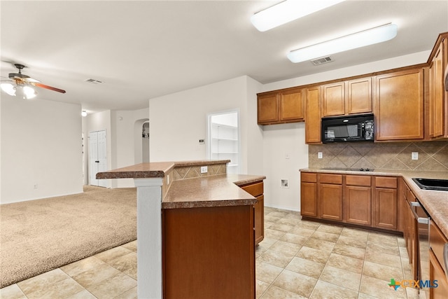 kitchen with ceiling fan, a center island, backsplash, light colored carpet, and black appliances