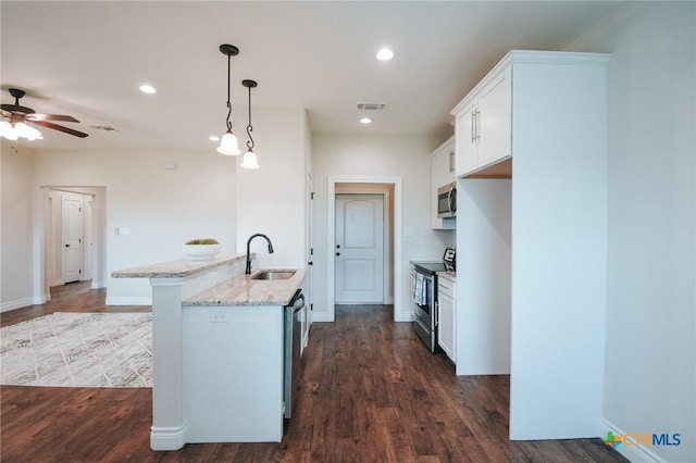 3611 Hanselman Rd, Victoria, TX 77901 - kitchen with stainless steel appliances, light stone countertops, white cabinets, dark wood-style flooring, and decorative light fixtures