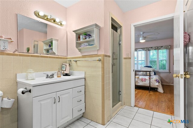 bathroom featuring walk in shower, hardwood / wood-style floors, tile walls, and ceiling fan