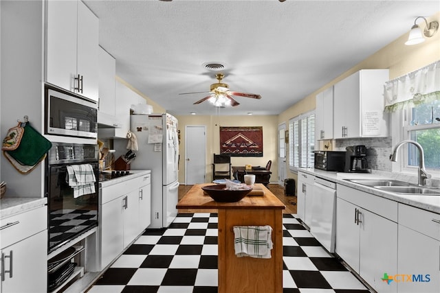 kitchen featuring white cabinets, decorative backsplash, black appliances, and sink