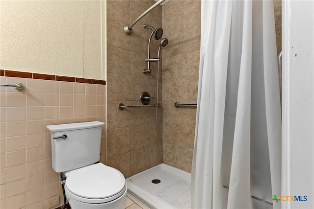 bathroom featuring toilet, tile walls, and curtained shower