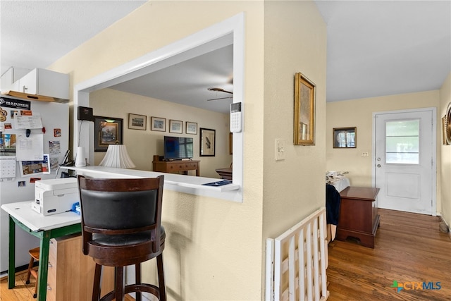 kitchen with white cabinetry, kitchen peninsula, a kitchen bar, hardwood / wood-style floors, and white refrigerator