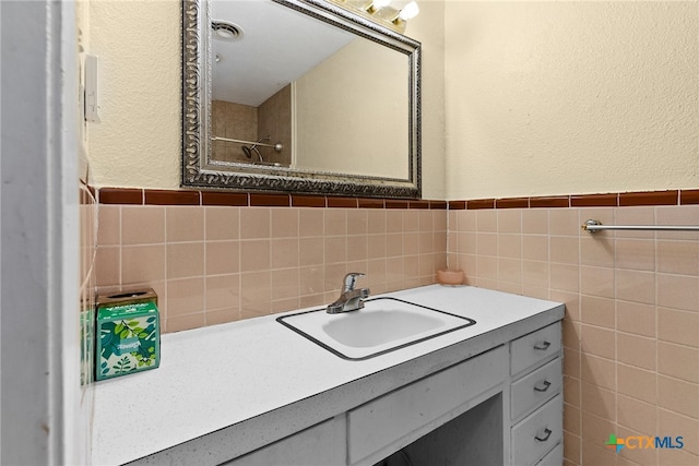 bathroom featuring vanity and tile walls