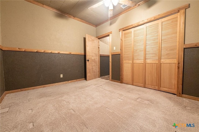 unfurnished bedroom featuring light carpet, ornamental molding, a closet, and ceiling fan