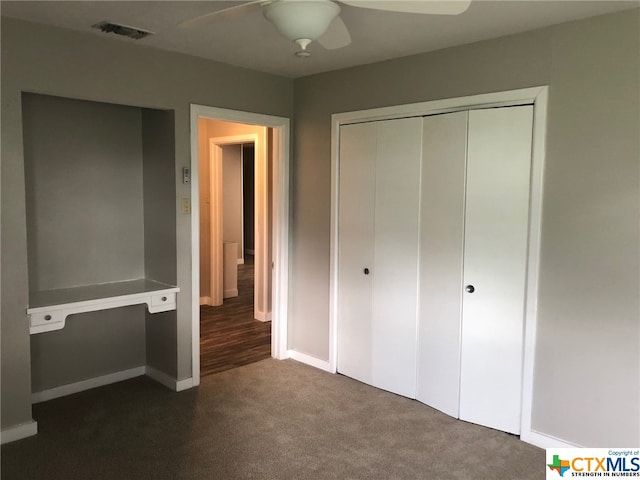 unfurnished bedroom with dark colored carpet, ceiling fan, and a closet