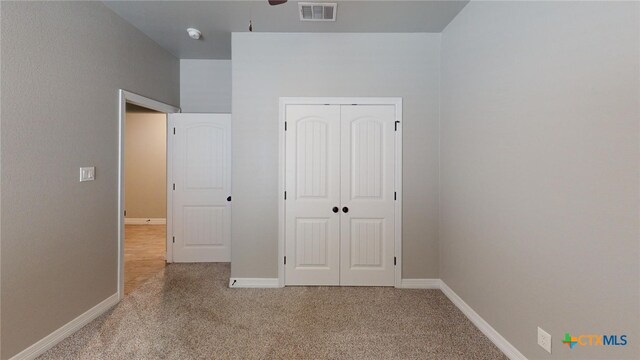 unfurnished bedroom featuring light carpet and a closet