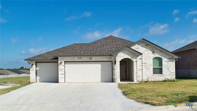 3826 Leming Ct, Temple, TX 76504 - french country home with an attached garage, concrete driveway, stone siding, a front lawn, and roof with shingles