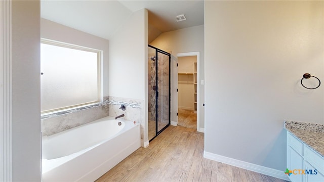 3826 Leming Ct, Temple, TX 76504 - full bathroom with a spacious closet, a garden tub, a shower stall, wood finished floors, and vaulted ceiling