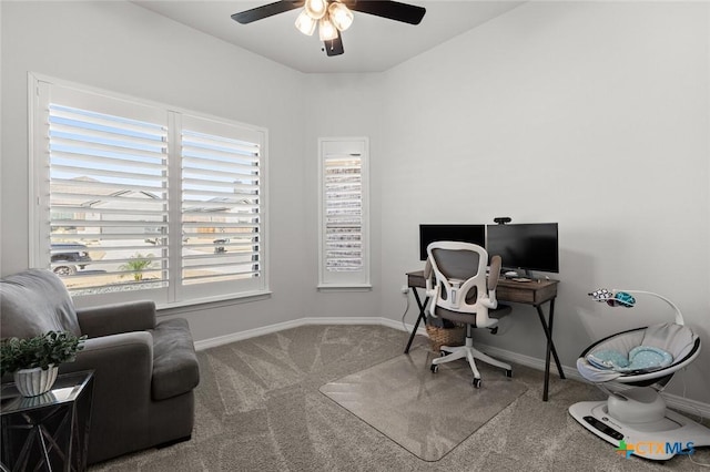 carpeted office space featuring a ceiling fan and baseboards