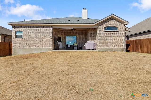 back of property featuring a yard, brick siding, fence, and a ceiling fan