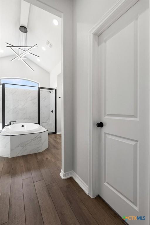 bathroom with lofted ceiling, wood finished floors, visible vents, baseboards, and a bath