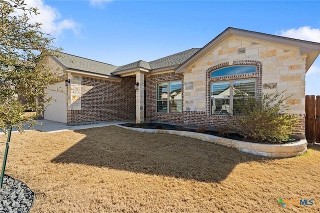 view of front of home featuring an attached garage, stone siding, fence, and brick siding