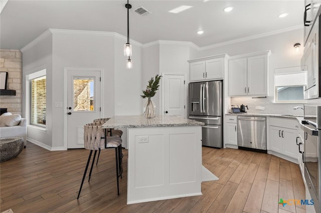 kitchen featuring white cabinets, a kitchen island, stainless steel appliances, and wood finished floors