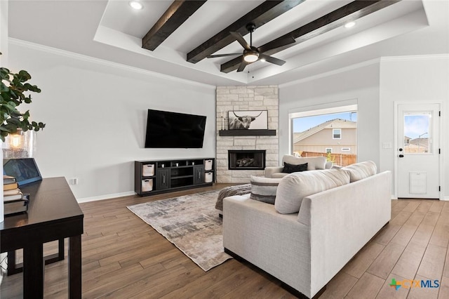 living room with beam ceiling, crown molding, a fireplace, wood finished floors, and baseboards