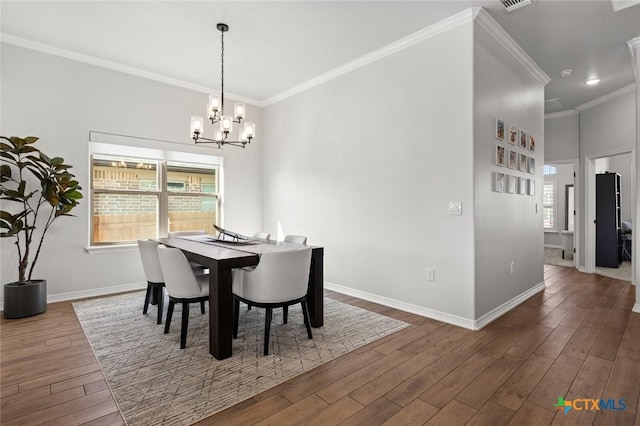 dining room featuring ornamental molding, a wealth of natural light, baseboards, and wood finished floors