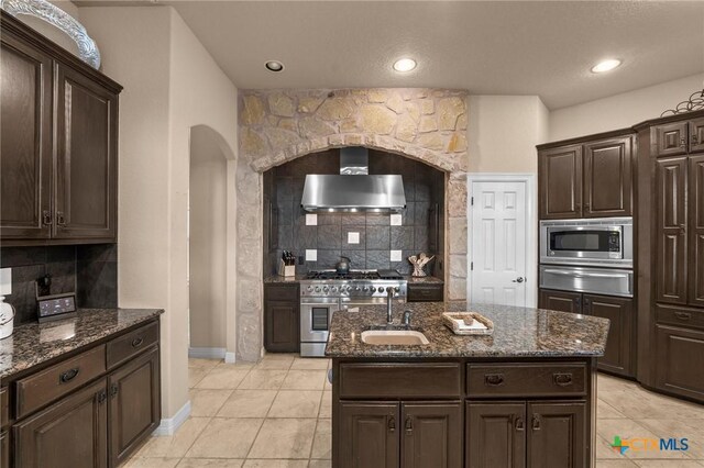 5310 River Oaks Dr, New Braunfels, TX 78132 - kitchen featuring wall chimney range hood, stainless steel appliances, a warming drawer, tasteful backsplash, and arched walkways