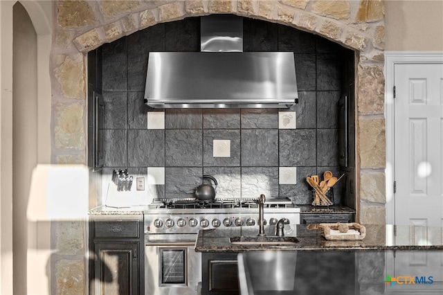 5310 River Oaks Dr, New Braunfels, TX 78132 - kitchen featuring wall chimney range hood, high end range, decorative backsplash, and dark stone counters