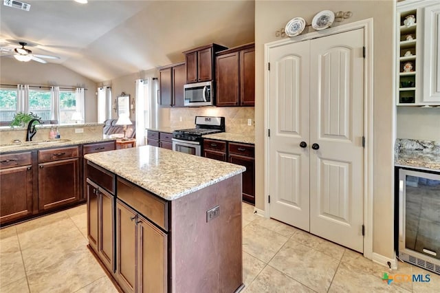106 Cobble Stone Ct, Victoria, TX 77904 - kitchen featuring appliances with stainless steel finishes, wine cooler, a sink, vaulted ceiling, and a center island
