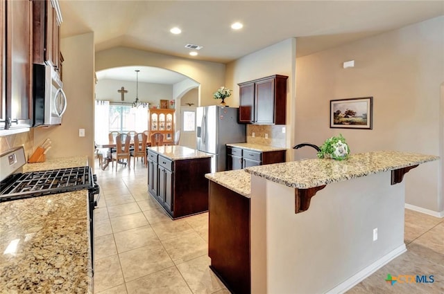 106 Cobble Stone Ct, Victoria, TX 77904 - kitchen with appliances with stainless steel finishes, arched walkways, a kitchen island, decorative backsplash, and a kitchen bar