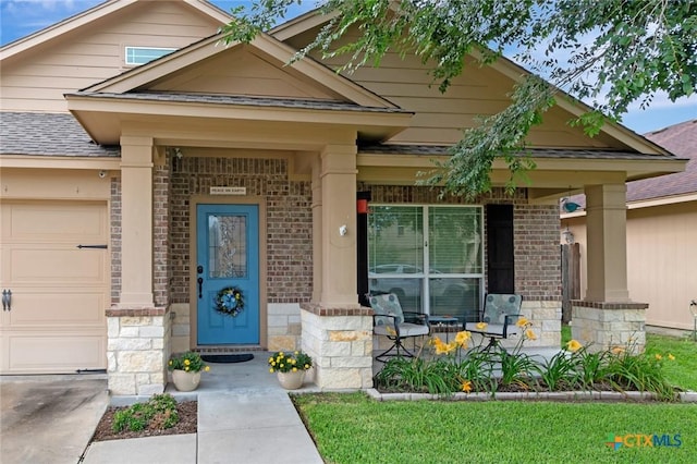 106 Cobble Stone Ct, Victoria, TX 77904 - property entrance with covered porch, a garage, stone siding, brick siding, and a shingled roof