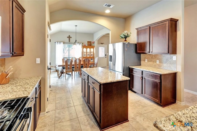 106 Cobble Stone Ct, Victoria, TX 77904 - kitchen featuring arched walkways, vaulted ceiling, stainless steel appliances, backsplash, and light stone countertops