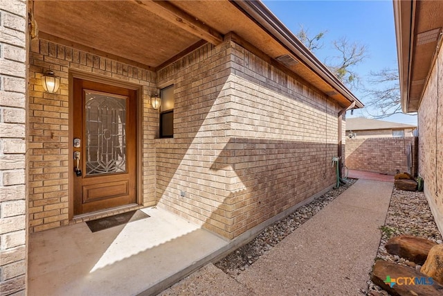 entrance to property with brick siding and fence