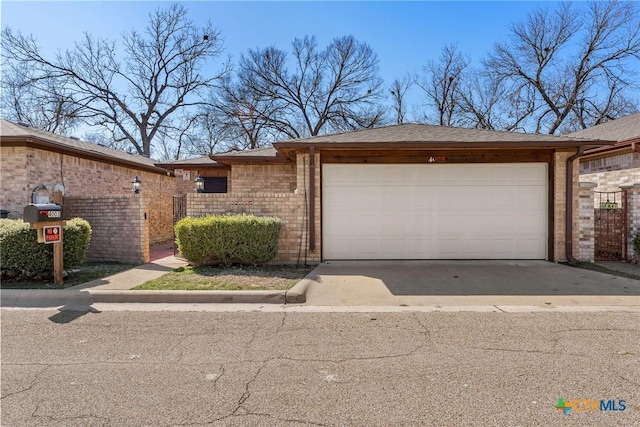 view of front of home with an attached garage, fence, concrete driveway, and brick siding