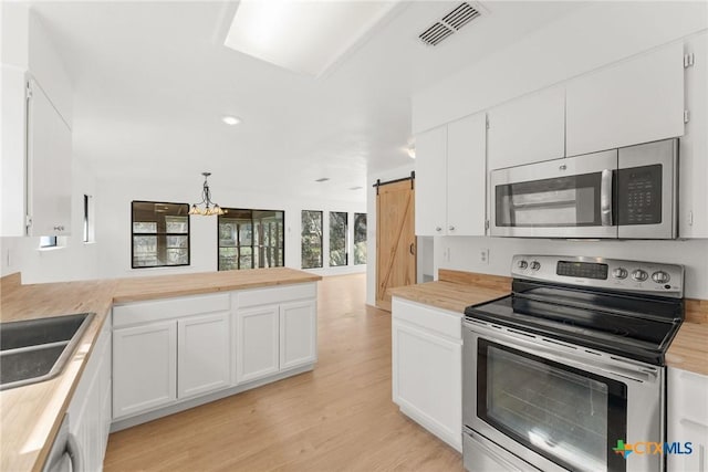 kitchen with stainless steel appliances, a barn door, butcher block counters, and visible vents