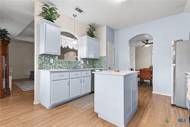 kitchen featuring appliances with stainless steel finishes, light hardwood / wood-style floors, hanging light fixtures, and sink