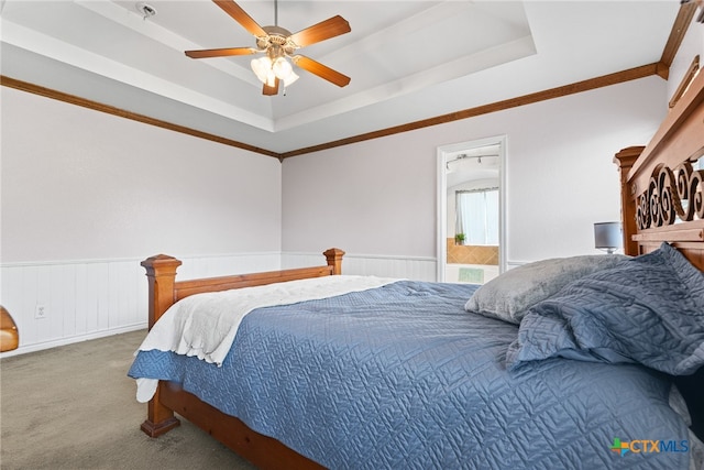 carpeted bedroom with ceiling fan, crown molding, and a tray ceiling