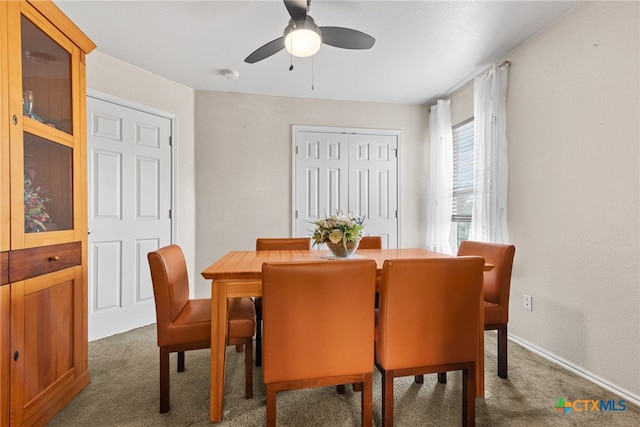 dining area with ceiling fan and dark carpet