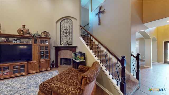 stairs with a tiled fireplace, tile patterned flooring, and a towering ceiling