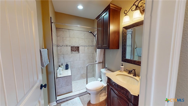 bathroom with tile patterned flooring, a tile shower, vanity, and toilet