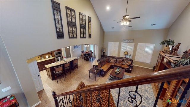 tiled living room with ceiling fan and high vaulted ceiling