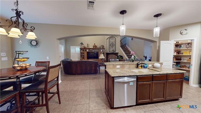 kitchen featuring light stone countertops, sink, stainless steel dishwasher, pendant lighting, and a kitchen island with sink