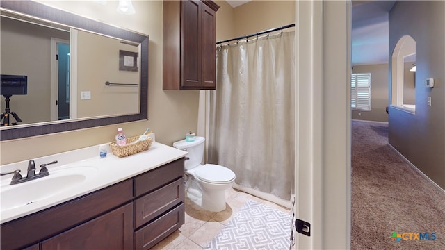 bathroom featuring tile patterned flooring, vanity, toilet, and walk in shower