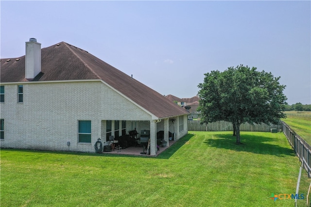 back of property with a lawn and a patio