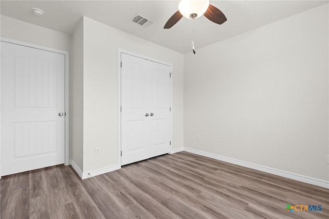 unfurnished bedroom featuring baseboards, visible vents, ceiling fan, and wood finished floors