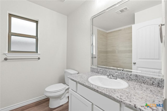 bathroom with visible vents, toilet, vanity, wood finished floors, and baseboards