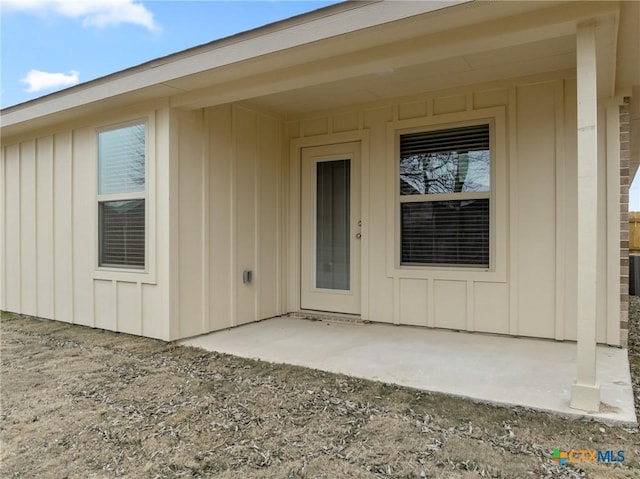 property entrance with board and batten siding and a patio