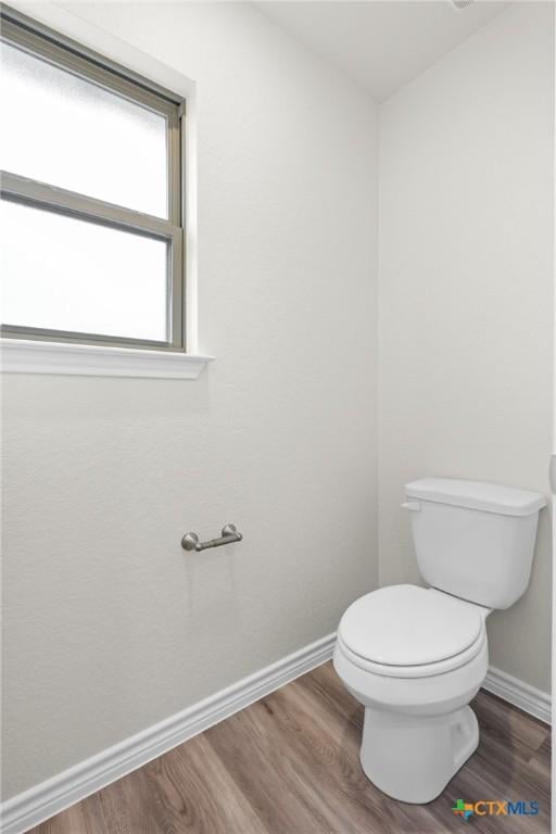 bathroom featuring wood finished floors, toilet, and baseboards