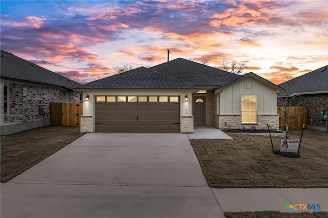 view of front of house featuring a garage, a shingled roof, concrete driveway, stone siding, and board and batten siding